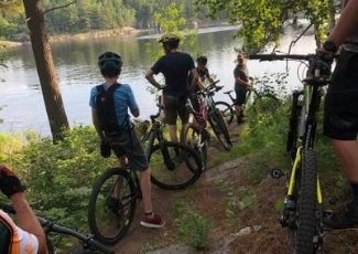 adults and children on bikes on a rustic trail along a lake